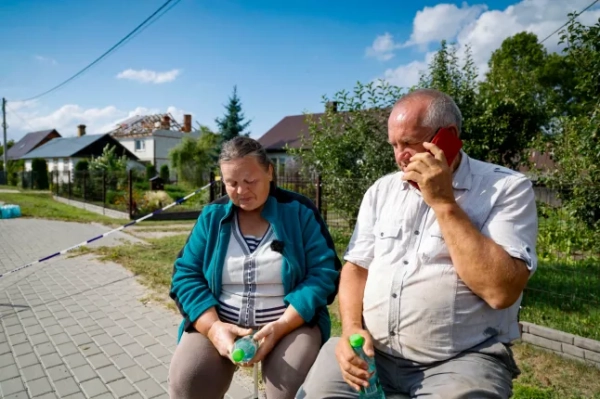 Аліція (ліворуч) сидить поруч зі своїм чоловіком Томашем Весоловським і розмовляє по телефону, поки поліція та армія оглядають пошкодження їхнього будинку, зруйнованого уламками збитого російського безпілотника в селі Вирики-Воля, східна Польща, 10 вересня 2025 року. Протиповітряна оборона НАТО допомогла протидіяти безпілотникам, які проникли в польський повітряний простір протягом ночі, і голова альянсу Марк Рютте підтримує зв'язок з Варшавою, повідомила речниця НАТО в середу. Прем'єр-міністр Польщі Дональд Туск заявив у середу, що порушення польського повітряного простору кількома російськими безпілотниками протягом ночі було серйозною провокацією, спрямованою проти ЄС та члена НАТО. (Фото Войтека Радванського / AFP) (Фото Войтека Радванського/AFP via Getty Images)