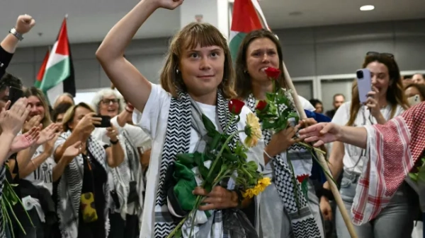 Шведська активістка із захисту клімату Грета Тунберг піднімає кулак після прибуття разом із активістами, які пливли на борту суден з гуманітарної флотилії, що прямувала до Гази, перш ніж їх зупинили та затримали ізраїльські війська, яких зустрів натовп прихильників, у зоні прибуття міжнародного аеропорту Афін 6 жовтня 2025 року. Міністерство закордонних справ Греції повідомило, що 161 громадянин з 16 європейських країн приземлився в Афінах 6 жовтня 2025 року після того, як був вигнаний Ізраїлем за участь у гуманітарній флотилії для Гази. У понеділок Ізраїль депортував ще активістів, які перебували на флотилії, що прямувала до спустошеної палестинської території, включаючи шведську активістку із захисту клімату Грету Тунберг. Флотилія з 45 суден мала на меті прорвати ізраїльську блокаду, щоб доставити допомогу до Гази, де, за словами Організації Об'єднаних Націй, після двох років руйнівного конфлікту настав голод (Фото Аріса МЕССІНІСА / AFP) (Фото ARIS MESSINIS/AFP via Getty Images)