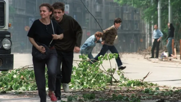 Мешканці Сараєво біжать перехрестям, відомим активністю снайперів після того, як 20 червня 1992 року в центр міста впав снаряд.