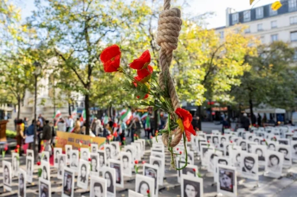 На цій фотографії зображено петлю з імітацією квітів поруч із портретними плакатами людей, страчених урядом Ісламської Республіки Іран.