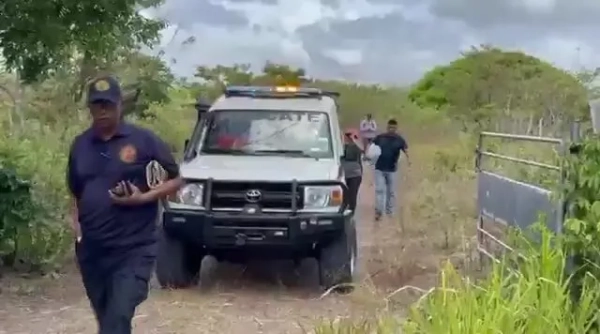 Місцева влада Панами патрулює трав'янисту ділянку, припаркувавши свій автомобіль біля воріт, що ведуть до поля.