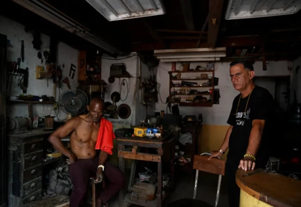Мануель та його колега-слюсар сидять у своїй майстерні під час відключення електроенергії через обвал національної електромережі Куби, повідомив оператор мережі країни, залишивши близько 10 мільйонів людей без електроенергії через нафтову блокаду, введену США, яка паралізувала і без того застарілу систему генерації острова, у Гавані, Куба, 16 березня 2026 року. REUTERS/Norlys Perez