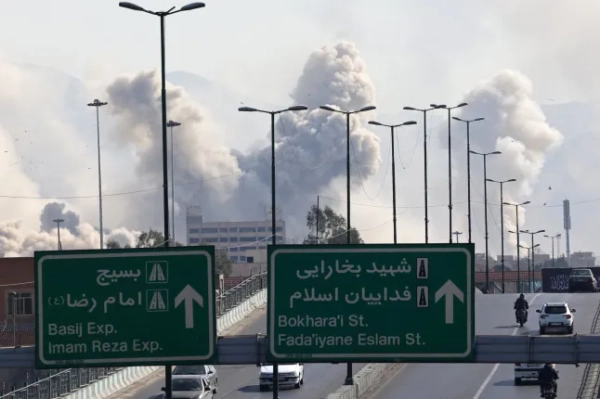 Транспортні засоби їдуть швидкісною автомагістраллю на тлі диму, що піднімається після удару по столиці Ірану Тегерану 5 березня 2026 року. Ізраїль завдав нових ударів по Тегерану, а Іран завдав ударів по курдських партизанських угрупованнях в Іраку 5 березня, коли війна на Близькому Сході охопила весь регіон. (Фото ATTA KENARE / AFP via Getty Images)