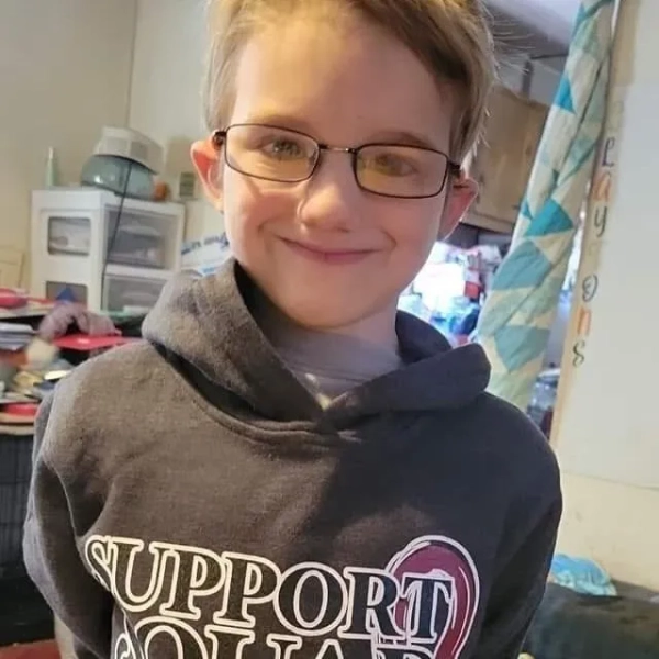 11-річного хлопчика привели до суду в кайданках, звинуваченого у вбивстві вітчима через Nintendo 7 Середній крупний план фотографії хлопчика-підлітка, який посміхається, носить окуляри та одягнений у сіру толстовку з капюшоном.