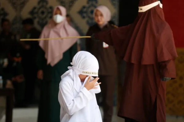 epa12689885 Реакція жінки з Ачеха на побиття батогом під час публічного покарання за порушення законів шаріату в Банда-Ачех, Індонезія, 29 січня 2026 року. Суддя Шаріатського суду Банда-Ачех засудив і покарав шістьох осіб від 23 до 140 ударів батогом кожного за статеві стосунки поза шлюбом та порушення законів шаріату. Ачех — єдина провінція в Індонезії, яка запровадила закони шаріату та вважає лесбійські, гомосексуальні, бісексуальні стосунки та секс поза шлюбом порушеннями закону. EPA/HOTLI SIMANDŽUNTAK