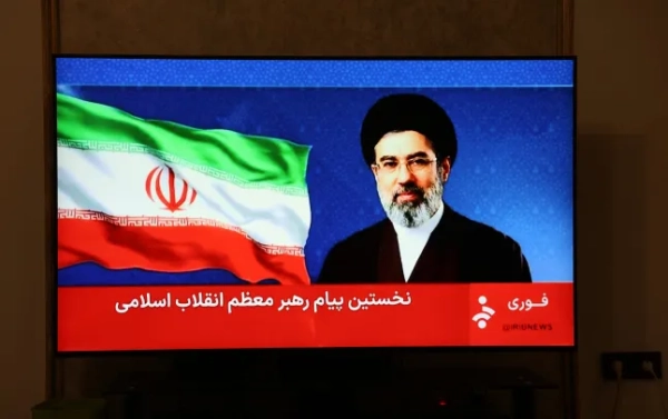 Це фото, зроблене в Тегерані, показує заяву нового верховного лідера Ірану Моджтаби Хаменеї, яку транслювали по телебаченню 12 березня 2026 року. Хаменеї, чий батько Алі Хаменеї загинув під час першої хвилі американо-ізраїльських атак на початку війни на Близькому Сході, закликав до того, щоб Ормузька протока залишалася заблокованою, а країни Перської затоки – закрити свої військові бази США. Хаменеї, який, як повідомляється, був поранений в результаті авіаудару, ще не з'являвся публічно з моменту свого висунення на посаду верховного лідера 8 березня 2026 року, а його зухвале звернення було зачитане диктором новин на державному телебаченні. (Фото AFP через Getty Images)