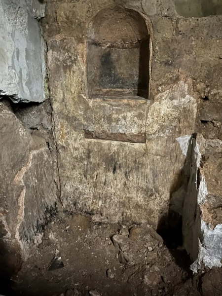 МАРК ВОРГАН Археологи, які працюють під історичним центром Кельна, виявили надзвичайно добре збережені римські залишки, зокрема рідкісну святиню домашніх богів, знайдену вперше в Північній Європі. За словами міських чиновників, знахідку було зроблено під час розкопок, пов'язаних з новим підземним маршрутом для відвідувачів у Єврейському музеї MiQua ??? LVR в Археологічному кварталі Кельна. Найбільш вражаючим відкриттям є ларарій – домашнє святилище, присвячене ларам, божествам-захисникам дому, – знайдене в колишньому римському преторії, палаці губернатора, який колись символізував імператорську владу в провінції Нижня Германія. Ларії були широко поширені в римських будинках по всьому Середземномор'ю. Цей, що датується II століттям, є унікальним на північ від Альп, а аналогічні приклади раніше знаходили лише в римських містах, похованих внаслідок вивержень вулканів, таких як Помпеї. Команда дослідників, яка брала участь у розкопках, каже, що кельнська знахідка майже безпрецедентна: сліди оригінального настінного розпису досі видно всередині вівтарної ніші. Невеликі отвори від цвяхів над і поруч із нішею свідчать про те, що колись святиню прикрашали гірлянди. Під ним чітка лінія розриву позначає місце, де спочатку був встановлений вівтарний стіл. Цю кам'яну плиту також було виявлено під час розкопок, і очікується, що її буде відновлено у початковому положенні. Відкриття були зроблені під час робіт, що проводилися містом Кельн у рамках підготовки до підземної екскурсії музею. Оскільки ділянки нового маршруту опускаються на незвичайну глибину, археологи змогли ідентифікувати споруди, які зазвичай втрачаються, будучи зруйнованими пізнішими будівельними роботами. У цьому випадку останки збереглися, оскільки вони вже були поховані в римські часи. Їхнє розташування на та під колишнім схилом річки Рейн означало, що вони були запечатані валами на початку античності, захищаючи їх від подальших пошкоджень. Серед інших значущих знахідок - фундамент апсиди, що належить до великої багатонефної римської базиліки, що датується IV століттям. Її товщина досягала чотирьох метрів, і спочатку вважалося, що вона була зроблена з римського литого бетону, відомого як opus caementicium. Детальне дослідження виявило замість цього шарувату конструкцію з туфу, базальту та вапняку, скріплену надзвичайно міцним розчином з цегли та гравію. До розкопок споруда виглядала на площі ратуші Кельна лише як невелике заглиблення. Зараз вона вперше доступна для відвідувачів. Археологи також виявили сходи кінця I століття, які були виявлені лише під час поточних робіт. Сходи колись з'єднували низовину поблизу Рейну з вищою місцевістю, пов'язаною з раннім преторієм. Точна точка, де закінчувалися сходи, залишається невідомою. Сходи рідко зберігаються в археологічних даних Кельна, оскільки більшість римських будівель збереглися лише на рівні фундаменту. Фахівці кажуть, що цей екземпляр зберігся завдяки сприятливим топографічним умовам, коли ранні римські споруди були поховані під час засипання ще в римський період. Очікується, що знахідки стануть центральною частиною підземної екскурсії, коли музей MiQua відкриється для публіки. У ньому представлено: Крупний план ларарію. Де: Кельн, Німеччина Коли: 24 лютого 2026 р. Авторство: Місто Кельн/Римсько-германський музей, Міхаель Віен/Зображення обкладинки **З усіх питань використання та запитів звертайтеся за адресою info@cover-images.com - +44 (0)20 3397 3000 ЛИШЕ ДЛЯ РЕДАКЦІЙНОГО ВИКОРИСТАННЯ. МАТЕРІАЛИ ДЛЯ ВИКОРИСТАННЯ ЛИШЕ РАЗОМ З РЕДАКЦІЙНОЮ СТАТТЮ. ВИКОРИСТАННЯ ЦИХ МАТЕРІАЛІВ ДЛЯ РЕКЛАМИ, МАРКЕТИНГУ АБО БУДЬ-ЯКИХ ІНШИХ КОМЕРЦІЙНИХ ЦІЛЕЙ СУВОРО ЗАБОРОНЕНО. АВТОРСЬКЕ ПРАВО НА МАТЕРІАЛИ ЗАЛИШАЄТЬСЯ У ЗАЯВЛЕНОГО ПОСТАЧАЛЬНИКА.**