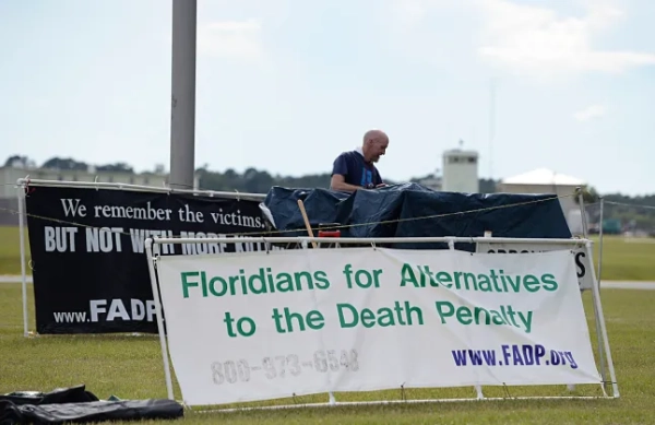 Марк Елліотт, директор організації «Флоридці за альтернативи смертній карі», розставляє плакати, поки протестувальники проти смертної кари демонструють перед в'язницею штату Флорида поблизу міста Старк, штат Флорида, у четвер, 10 липня 2014 року. Протестувальники чекали на страту Едді Вейна Девіса, який викрав 11-річну Кімберлі Вотерс і вбив її 3 березня 1994 року в Лейкленді, штат Флорида. (Фото AP/Філ Сендлін)