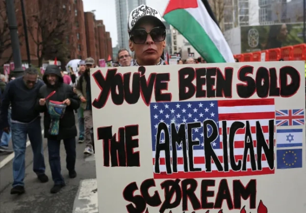 ЛОНДОН, АНГЛІЯ – 7 БЕРЕЗНЯ: Протестувальник тримає плакат з написом «Вам продали американський крик» під час мітингу «Зупиніть війну» проти ударів по Ірану 7 березня 2026 року в Лондоні, Англія. Протестувальники зібралися в центрі Лондона, щоб висловити свою думку проти того, що вони вважають безрозсудною та незаконною війною Дональда Трампа проти Ірану, маршируючи від Вестмінстера до посольства США. (Фото Мартіна Поупа/Getty Images)