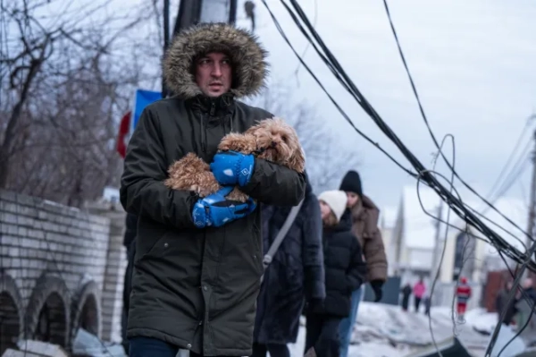 КИЇВ, УКРАЇНА – 22 ЛЮТОГО: Місцевий мешканець несе свою собаку на місці російського ракетного обстрілу в Києві, Україна, 22 лютого 2026 року. Внаслідок обстрілу загинула 1 людина, 15 людей отримали поранення, серед них 4 дітей. (Фото Данила Антонюка/Anadolu via Getty Images)