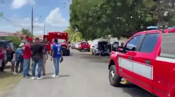 Широкий план, що показує групу людей, що стоять на дорозі, оточену червоними автомобілями екстреної допомоги