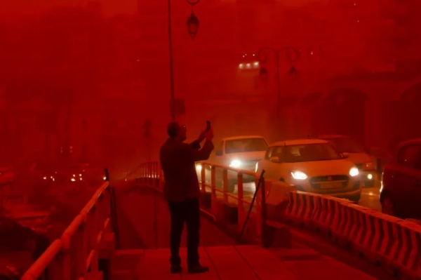 epa12865170 Чоловік фотографує місто Іракліон, вкрите червоним пилом з Африки, на острові Крит, Греція, 1 квітня 2026 року. Три міжнародні рейси довелося перенаправити до альтернативних аеропортів через низьку видимість, спричинену африканським пилом. EPA/НІКОС ХАЛКІАДАКІС