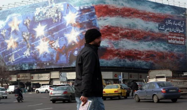 epa12679586 Люди проходять повз великий антиамериканський білборд на площі Енкелаб у Тегерані, Іран, 25 січня 2026 року. Президент США Дональд Трамп поновив погрози військовими діями проти Ірану після антиурядових протестів. Іран переживає загальнонаціональне відключення інтернету, яке почалося 8 січня 2026 року на тлі посилення хвилі антиурядових протестів. EPA/ABEDIN TAHERKENAREH
